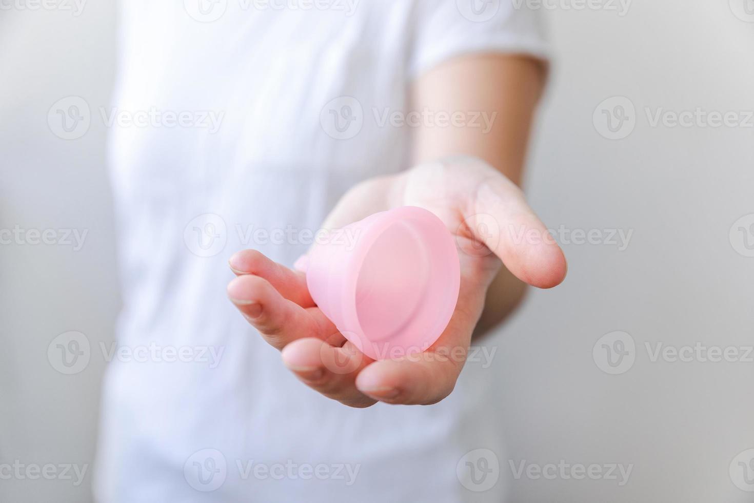 mão de uma mulher segurando o copo menstrual rosa isolado no fundo branco.  mulher moderna alternativa eco ginecológica higiene no período de  menstruação. recipiente para sangue na mão da menina. 5427428 Foto